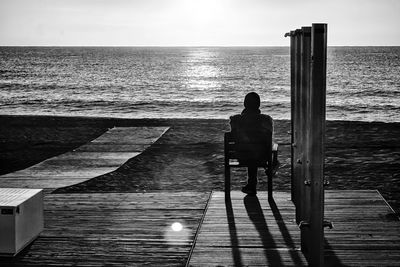 Rear view of man standing on jetty against sea