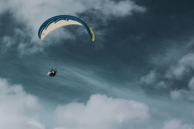 Low angle view of person paragliding against sky