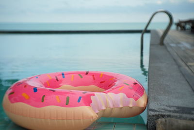 Close-up of pink floating on swimming pool against sea