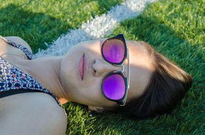 Beautiful girl in sunglasses is lying on the grass