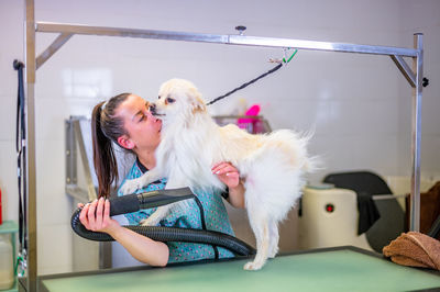 Animal groomer embracing dog at salon