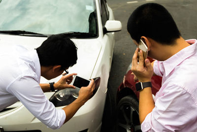 Men using mobile phone against crashed cars