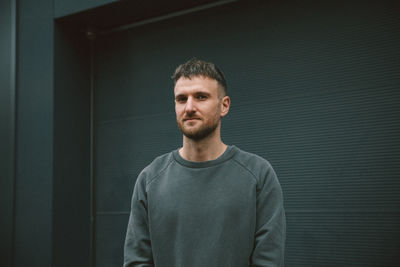 Portrait of handsome man standing against wall