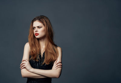 Portrait of young woman against black background