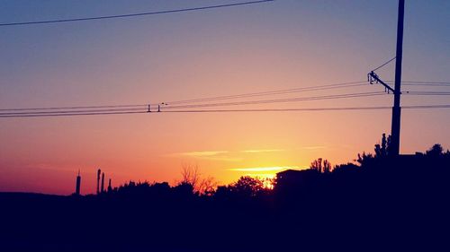 Silhouette electricity pylon against sky during sunset