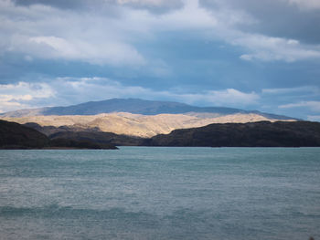 Scenic view of sea by mountains against sky