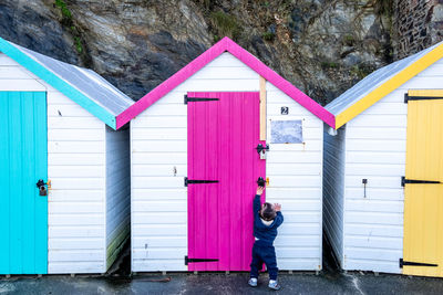 Rear view of baby boy reaching for beach hut door lock