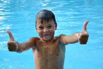 Portrait of shirtless boy gesturing in swimming pool