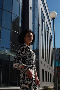 Side view of young woman standing against building in city