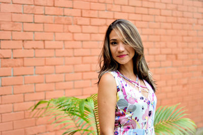 Portrait of young woman standing against wall