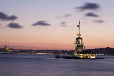 Illuminated building against sky during sunset