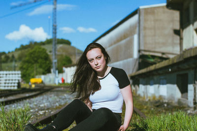 Portrait of young woman sitting on railroad track