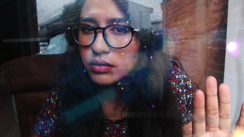 Portrait of beautiful young woman seen through glass window