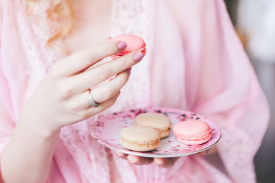 Midsection of woman holding macaroons in plate