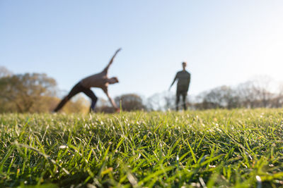 People relaxing on field against clear sky