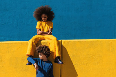 Full length of woman standing against yellow wall