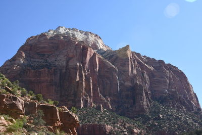 Low angle view of rocky mountains against blue sky