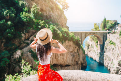 Woman wearing hat standing against waterfall