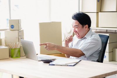 Young man using mobile phone while sitting on table