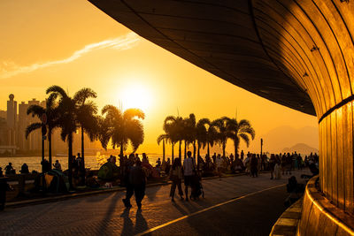 People walking alone harbour side in sunset hour