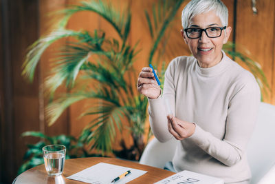 Midsection of woman holding glass while sitting on table