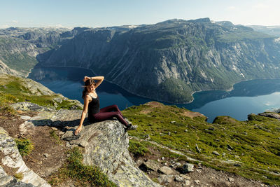 People sitting on rock against mountain range