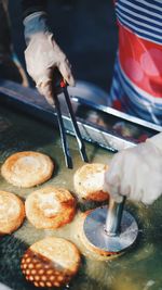 Close-up of person preparing korean street food.