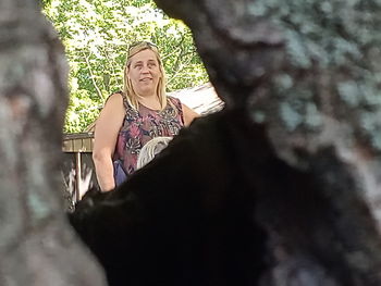 Midsection of woman sitting on tree trunk