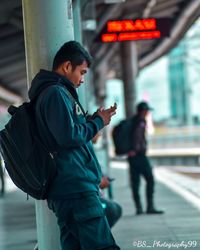 Side view of man using mobile phone in city