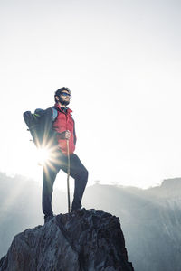 Young traveler in red snow jacket and a backpack standing on blue isolated background. 