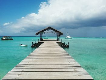 Gazebo on pier over sea against cloudy sky