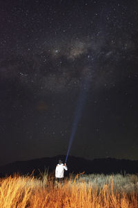 Young man in the field observing the milky way with a flashlight in hi