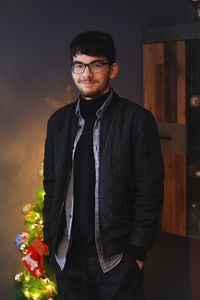 Portrait of young man standing against wall
