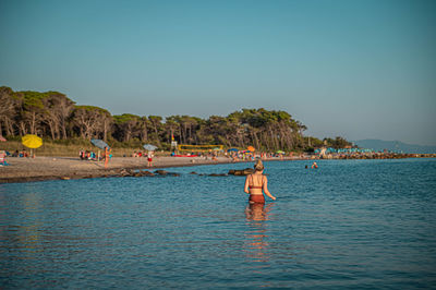 People on sea against clear sky