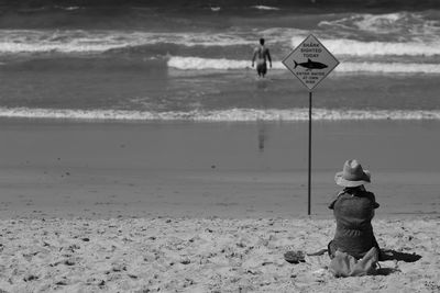 Rear view of woman sitting on beach