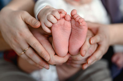 Hands of mom and dad are holding the foots of a little baby. newbourne concept