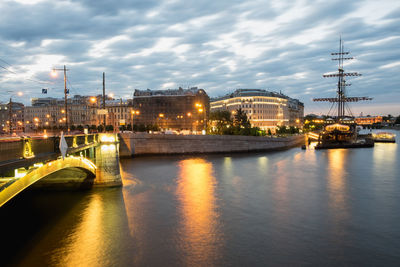 Illuminated bridge over river against sky in city