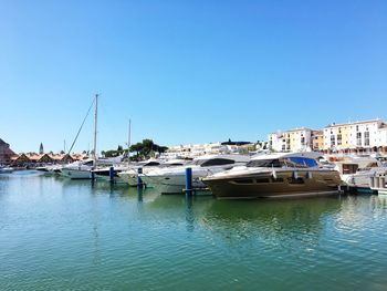 Sailboats moored at harbor against clear blue sky