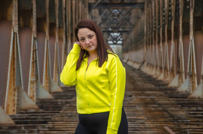 Portrait of young woman standing on railroad bridge doing exercises 