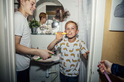 Portrait of boy brushing teeth near bathroom sink