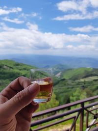 Midsection of man holding drink against sky