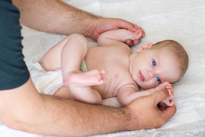 Low section of baby boy lying on bed