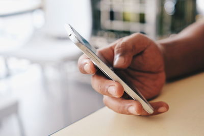 Close-up of person holding mobile phone on table 