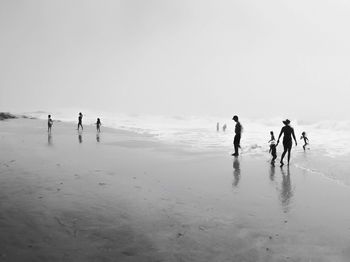 People walking on beach against sky