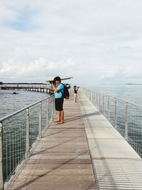 Man standing on pier over sea against sky
