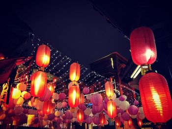 Low angle view of illuminated lanterns hanging against sky at night