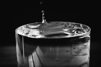 Close-up of water falling in glass over black background