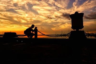 Silhouette men standing against orange sky during sunset