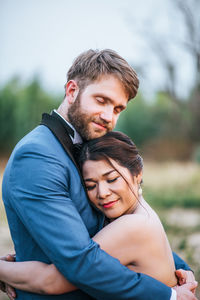 Smiling newlywed couple embracing with eyes closed