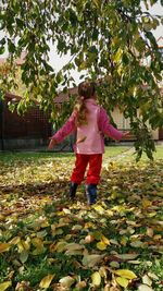 Full length of woman with leaves on tree